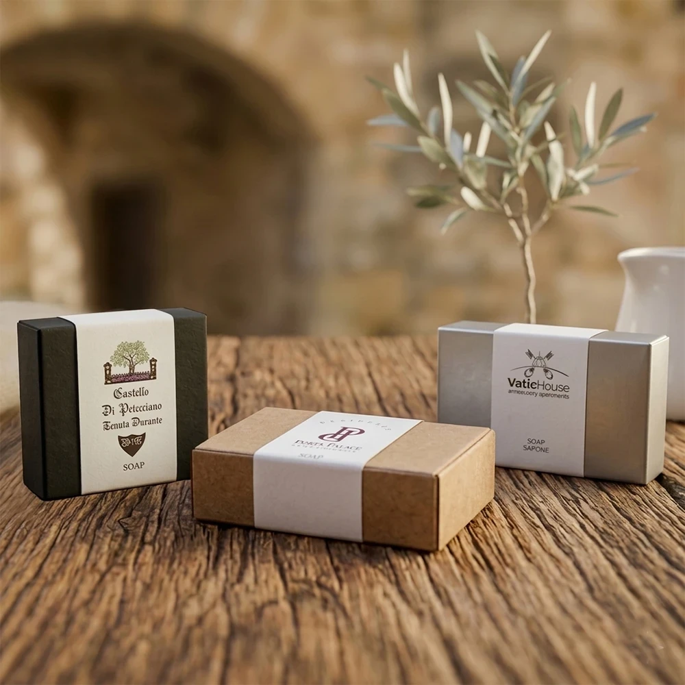 Esempi di sapone per hotel personalizzato in scatoline nera, kraft e argento con fascetta bianca e loghi Castello di Petecciano, VatiHouse e Forte Palace.
