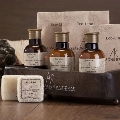 Set completo di kit benvenuto hotel in vassoio di legno: flaconi ambrati, saponette e sacchetti in carta kraft personalizzati All Seasons Residence.