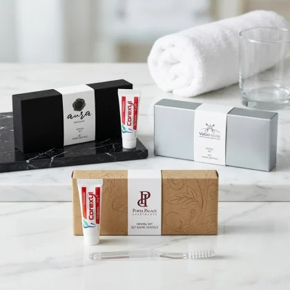 Tre modelli di kit igiene orale hotel con fascetta bianca personalizzata su basi nero soft-touch, argento e kraft con spazzolino trasparente e dentifricio Corexyl.