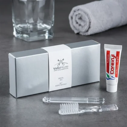 Kit igiene orale hotel in scatolina argento metallizzato con nastrino bianco personalizzato VaticHouse, spazzolino trasparente e dentifricio Corexyl.