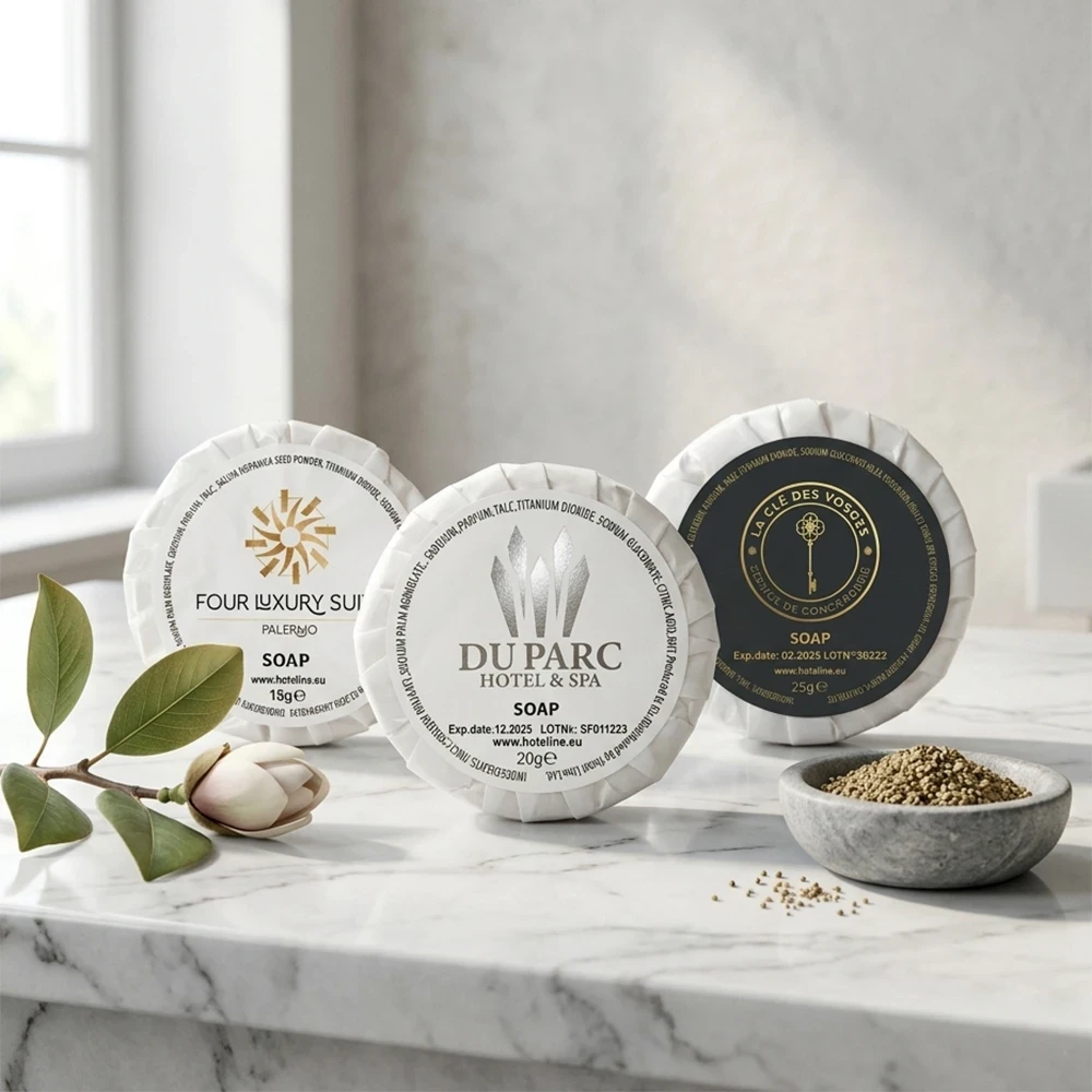 Esempi di saponette hotel personalizzate plissettate con loghi Du Parc, Four Luxury Suite e La Cle Des Vosges su marmo bianco.