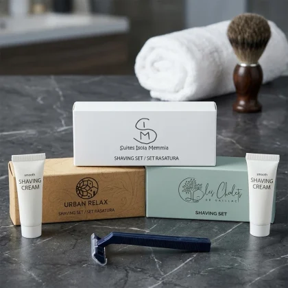 Tre modelli di scatoline per set rasatura hotel: bianco Isola Memmia, kraft Urban Relax e azzurro Les Chalets con rasoio blu e crema Smooth.