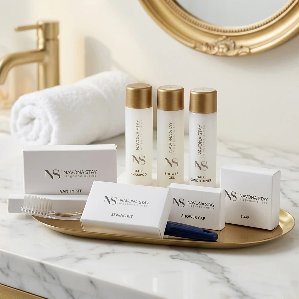 Kit benvenuto hotel lusso con flaconi bianchi satinati e tappo oro, scatoline bianche lisce personalizzate Navona Stay su vassoio dorato e marmo.