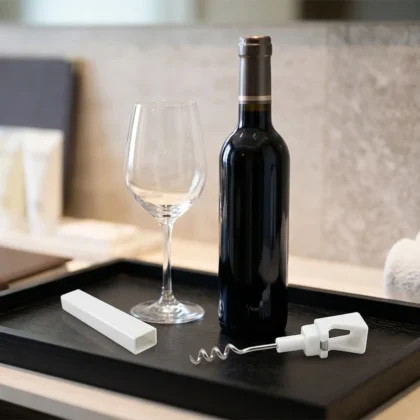 Cavatappi tascabile e apribottiglie bianco per frigobar hotel e B&B su vassoio di benvenuto con bottiglia di vino.